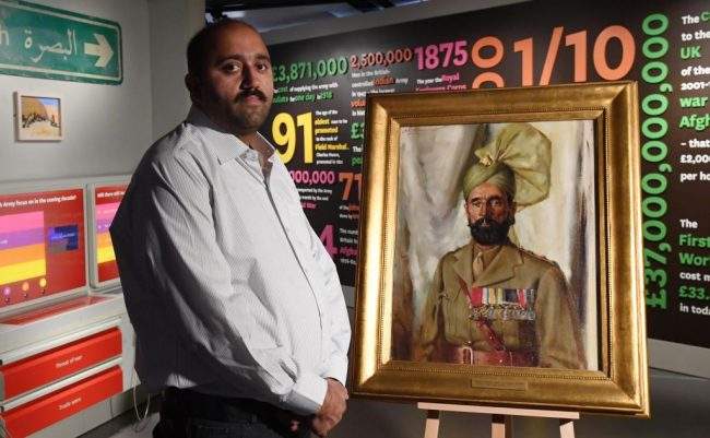 Ali Nawaz Chaudhary stands next to a portrait of his grandfather Khudadad Khan, the first Indian Recipient of the Victoria Cross, at the National Army Museum in London, May 17, 2018.