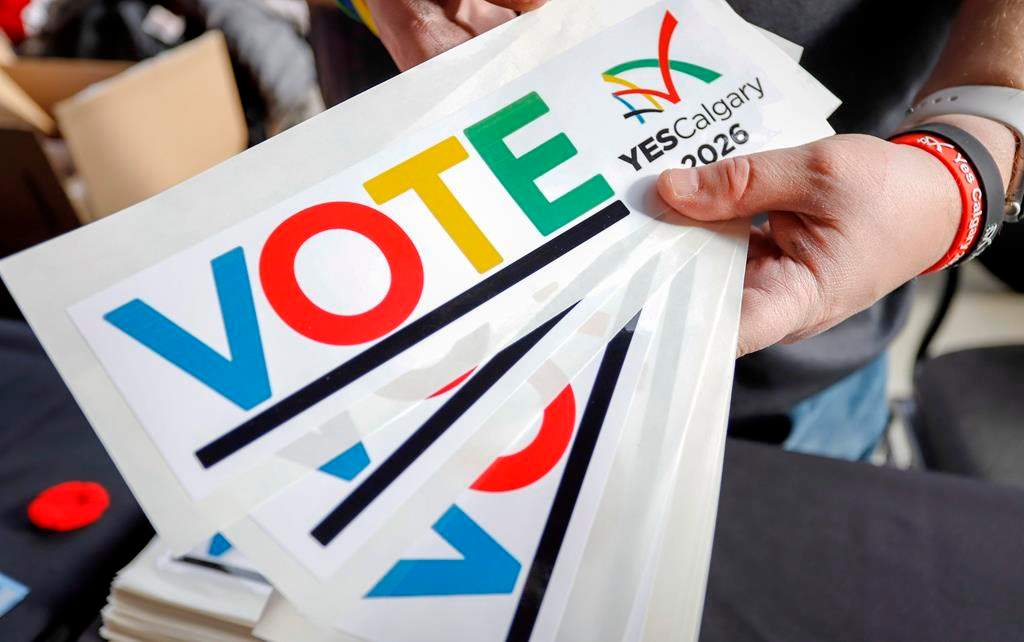 Bumper stickers are handed out during a rally in support of the 2026 Winter Olympic bid in Calgary on Nov. 5, 2018. The city ended up deciding against submitting an official bid after more than 56 per cent of voters rejected the idea in a public plebiscite.