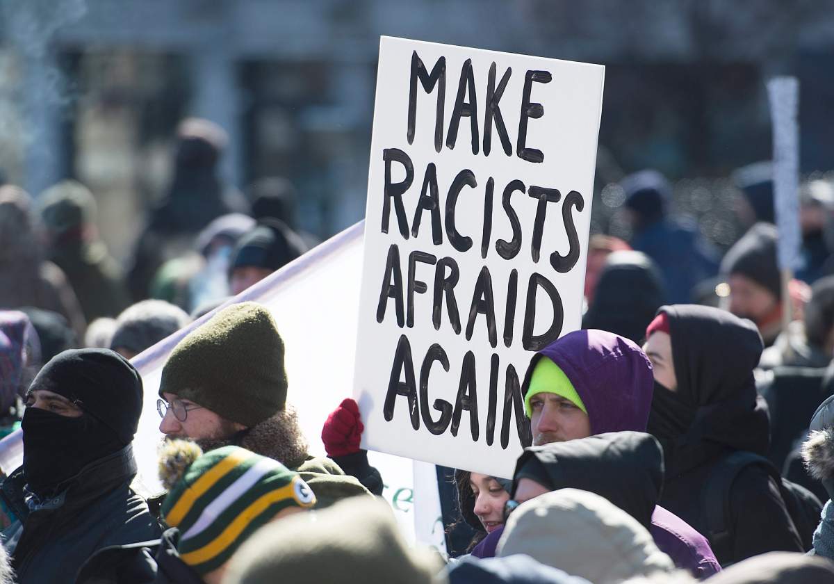 People hold up a signs during a demonstration to oppose motion M103 in Montreal, Saturday, March 4, 2017.