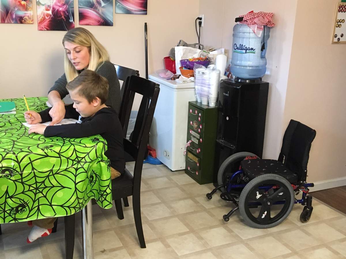 Shannon Ranger helps her son Matthew Gessner with homework. Matthew’s wheelchair can be seen against the wall.