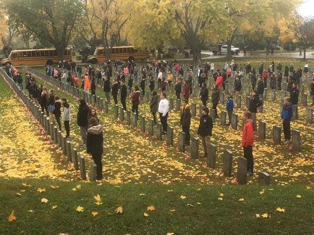 Students from Aldershot School place poppies on the graves of Canadian soldiers as part of the No Stone Left Alone initiative.