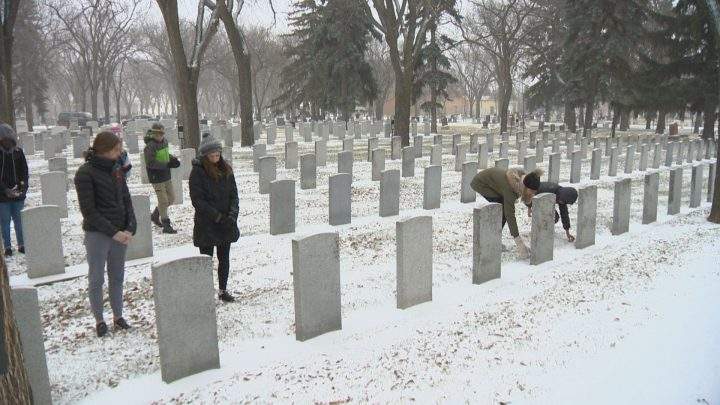 Students place poppies on headstones during No Stone Left Alone ceremony.