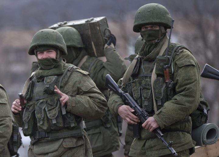 In this March 19, 2014 file photo, a pro-Russian soldier flashes a victory sign while marching near a Ukrainian army base in Perevalne, Crimea.