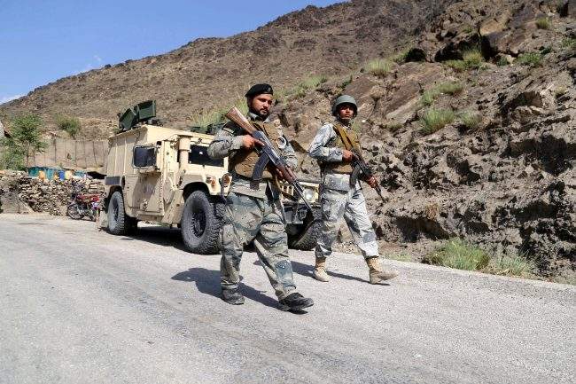 In this Oct. 13, 2017, file photo, Afghan security officials stand guard on a highway in Kunar province, Afghanistan.  