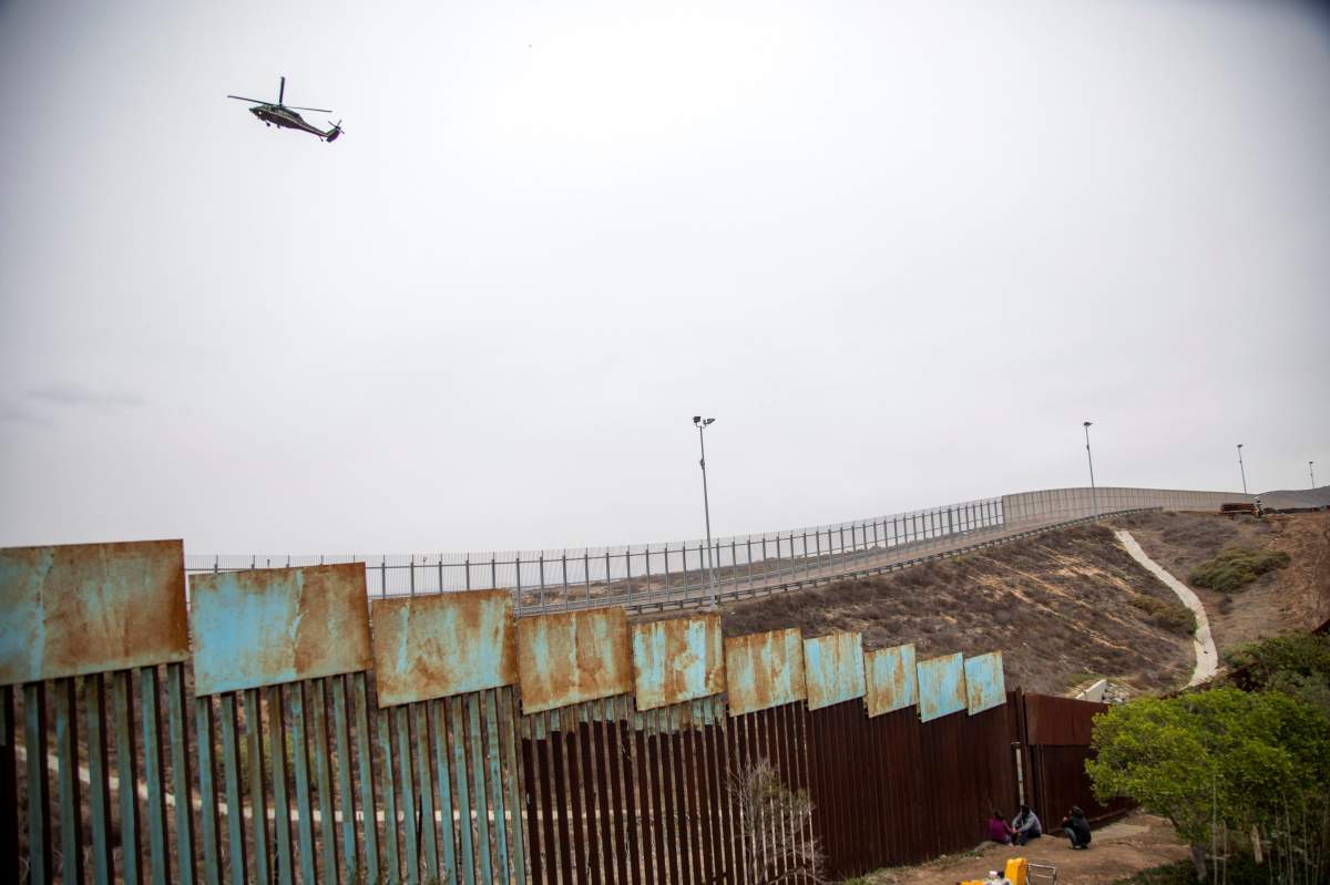 Members of the Central American migrant caravan sit next to the border wall in Tijuana, Mexico, 05 December 2018.