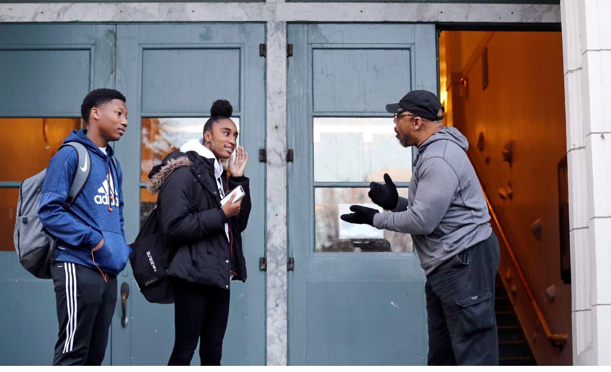 Teaching assistant Leonardo Baker, right, greets students arriving at Franklin High School Wednesday morning, Dec. 12, 2018, in Seattle. High school students are getting more sleep in Seattle, according to a study on later school start times.