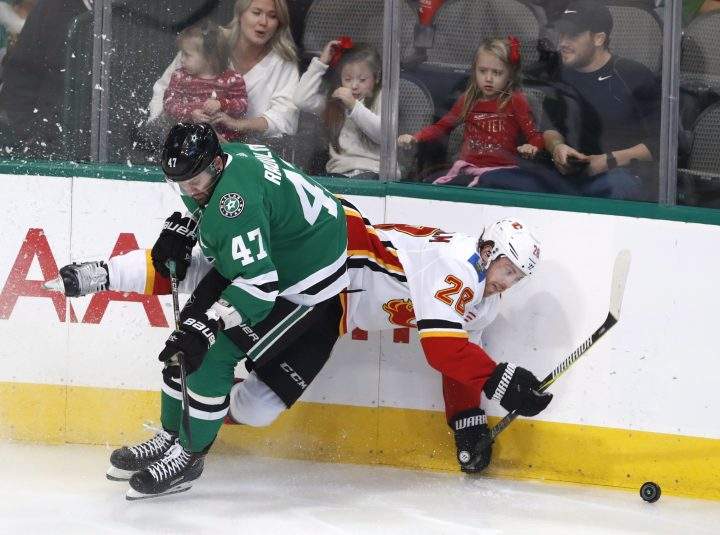 Calgary Flames center Elias Lindholm (28) is knocked down by Dallas Stars right wing Alexander Radulov (47) during the first period of an NHL hockey game in Dallas, Tuesday, Dec. 18, 2018.