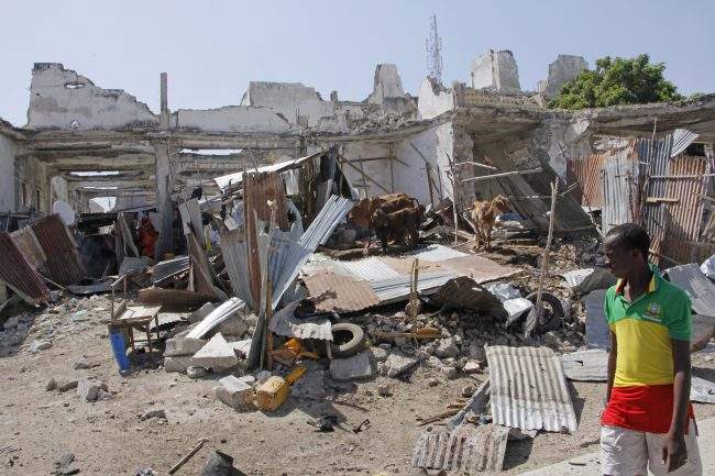 A man walks near destroyed buildings after a bomb blast in the capital city of Mogadishu, Somalia, Saturday, Dec. 22, 2018.