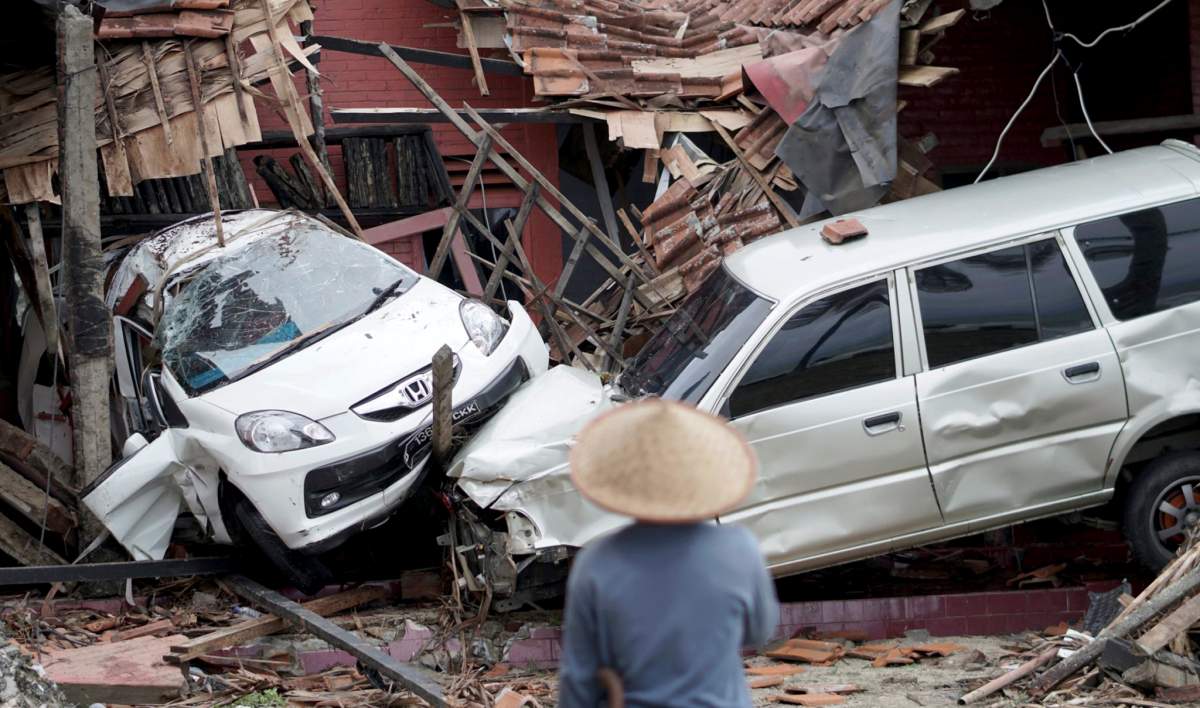 An Indonesian man looks at ruined vehicles after a tsunami hit Sunda Strait in Anyer, Banten, Indonesia, Dec. 23, 2018.