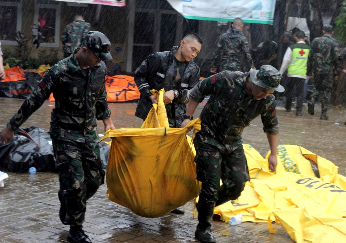 Indonesian soldiers carry a body bag containing the body of a tsunami victim in Carita, Indonesia, Sunday, Dec. 23, 2018.