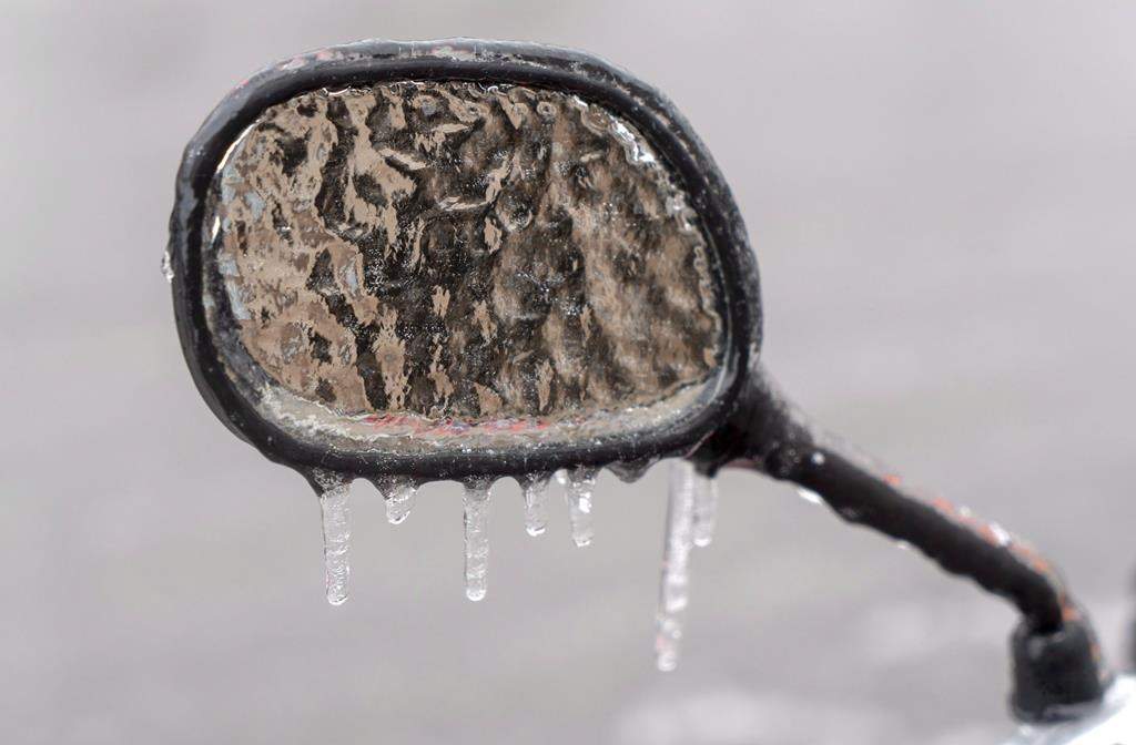 The ice-covered mirror of a a motorcycle is seen following freezing rain Monday, April 16, 2018 in Montreal.
