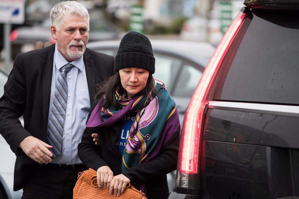Huawei chief financial officer Meng Wanzhou, right, arrives at a parole office with a member of her private security detail in Vancouver, on Wednesday December 12, 2018. THE CANADIAN PRESS/Darryl Dyck