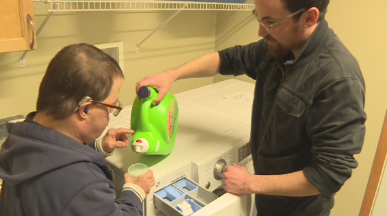 Support Staff worker Rob Edwards assists his client Gimmy Vaccaro with his laundry.