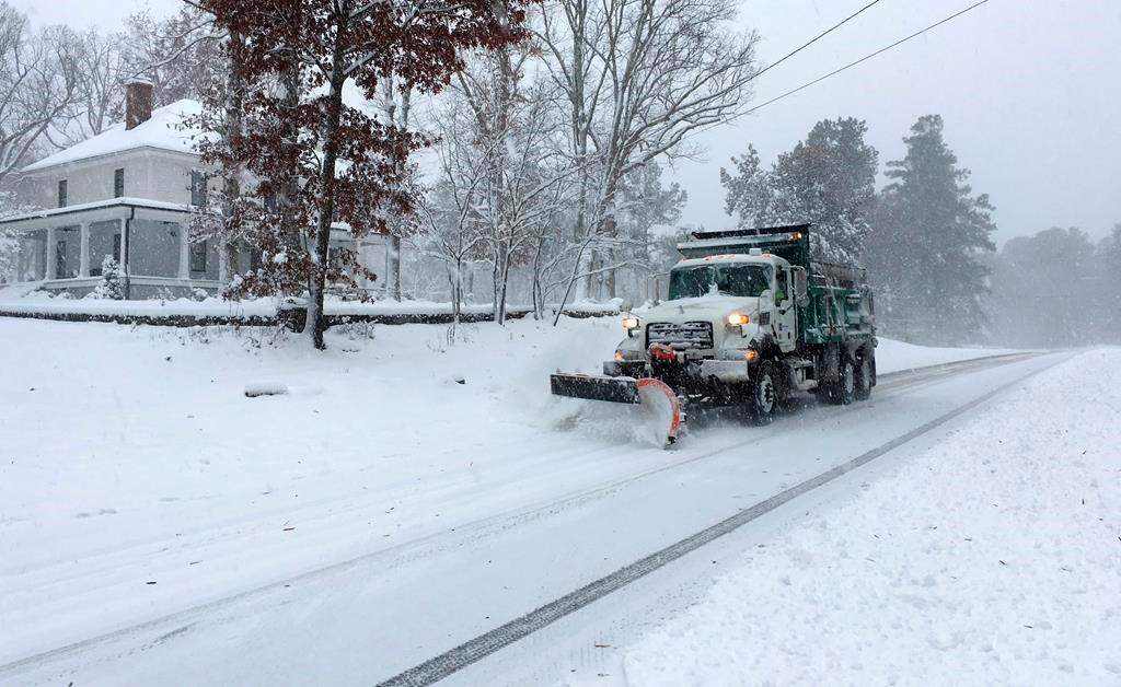 A snow plow moves snow on a wintery street.