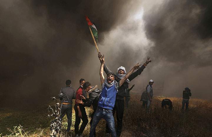 Palestinian demonstrators shout during clashes with Israeli troops at a protest demanding the right to return to their homeland, at the Israel-Gaza border east of Gaza City, April 6, 2018.