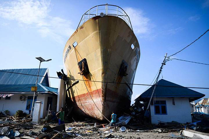 Quake survivors make their way past a washed out passenger ferry in Wani, Indonesia’s Central Sulawesi on October 3, 2018, after an earthquake and tsunami hit the area on September 28.