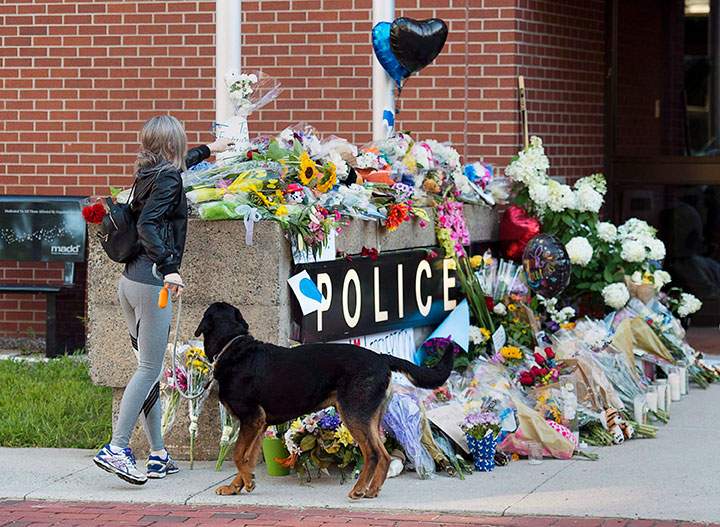Flowers are placed on a makeshift memorial outside the police station in Fredericton on Saturday, Aug. 11, 2018.