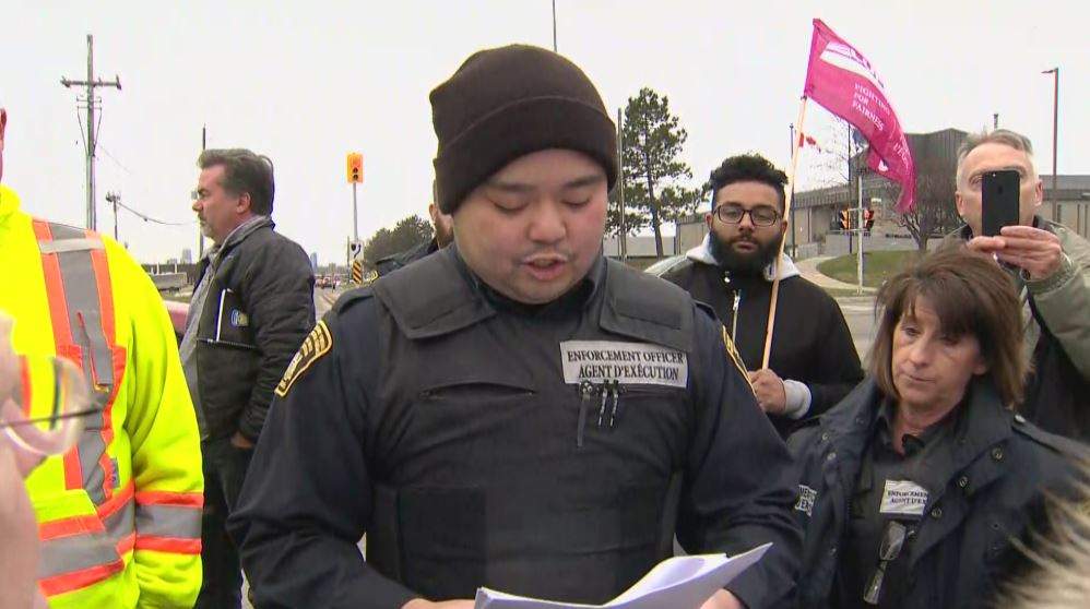 An enforcement officer reads out an injunction declaring the blocking of entrances to the facility illegal.