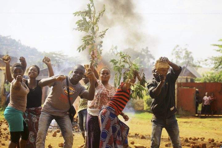 Protesters act in front of the camera after setting a burning barricade in the Eastern Congolese town of Beni Thursday Dec. 27, 2018.