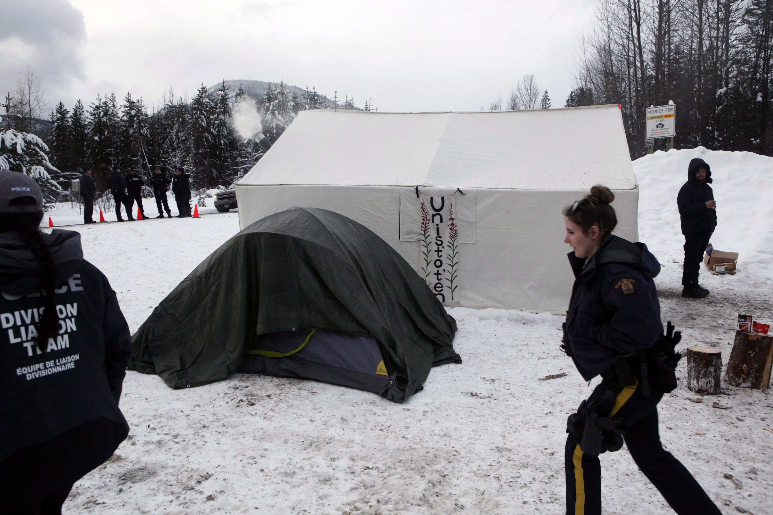 RCMP members gather at a Wet’suwet’en checkpoint after representatives from Coastal GasLink and contractors make their way through an exclusion zone at the 27 kilometre marker towards the Unist’ot’en camp to remove barriers on a bridge over the Morice River, southwest of Houston, B.C., on Friday, January 11, 2019. THE CANADIAN PRESS/Chad Hipolito