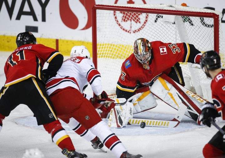 Carolina Hurricanes’ Saku Maenalanen, centre, of Finland, has his shot stopped by Calgary Flames goalie David Rittich, of the Czech Republic, during first period NHL hockey action in Calgary, Tuesday, Jan. 22, 2019.