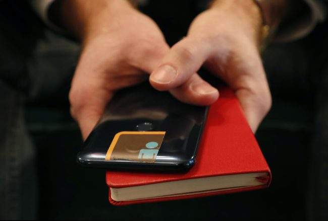 John Scott-Railton, a senior researcher at the Citizen Lab, holds his cell phone which has its camera blocked by an adhesive sticker, as he poses for a photograph, Jan. 17, 2019, in New York. 


