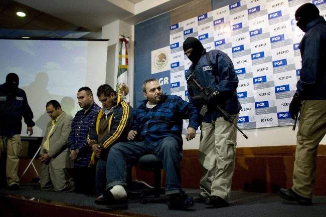 A man identified as Jesus Zambada Garcia, one of the top leaders of the Sinaloa drug cartel, is led away by a masked police officer after being presented to the media in Mexico City, Oct. 22, 2008.