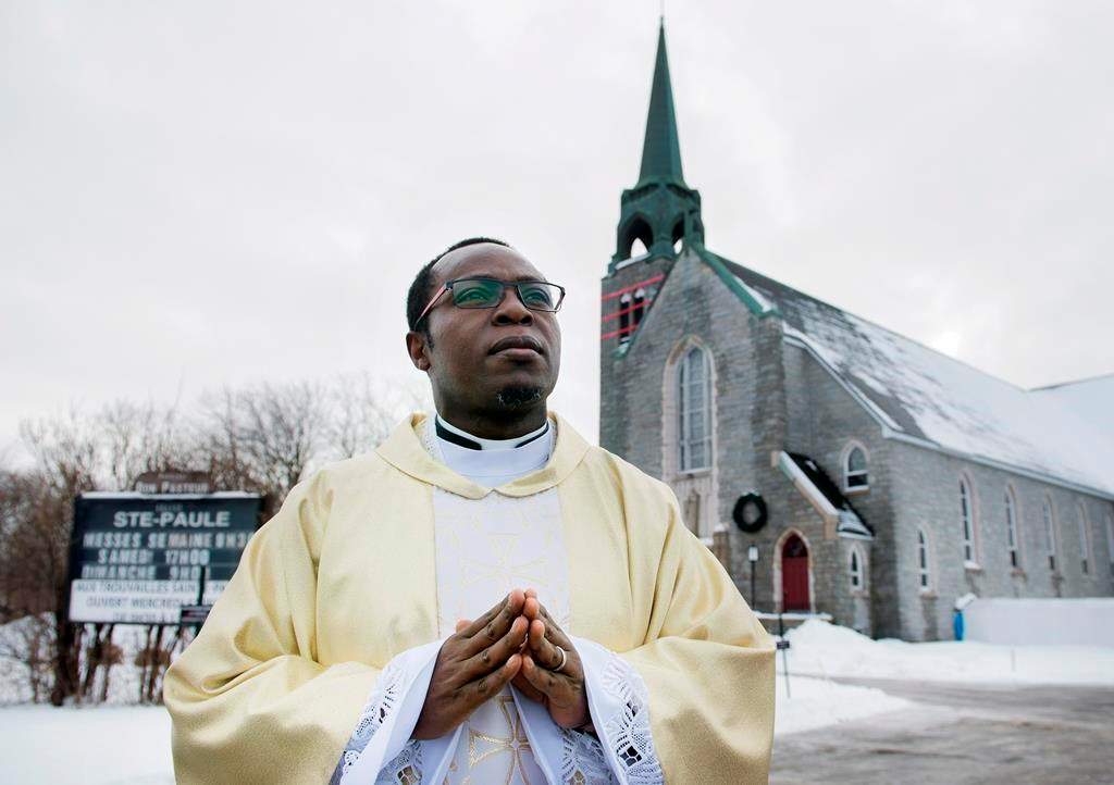Father Gauthier Elleme poses outside Sainte-Paule's church in Saint-Jerome, Que., Saturday, January 5, 2019.
