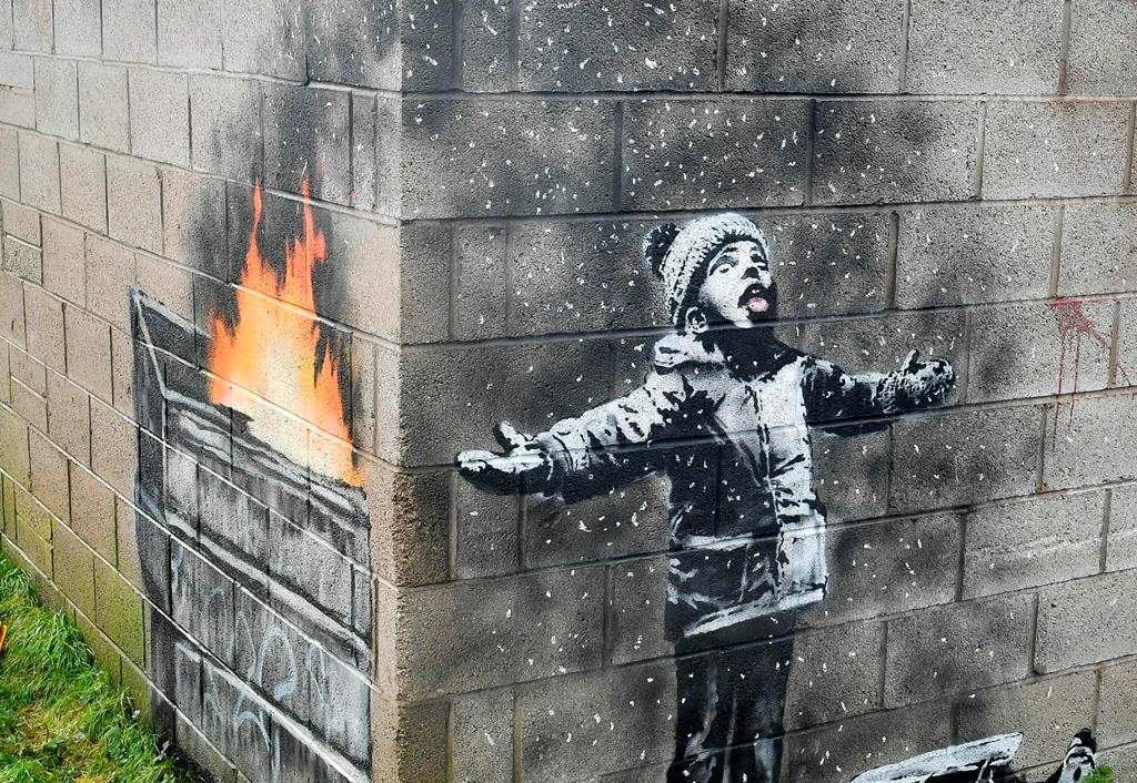 FILE - In this file photo dated Dec, 20, 2018, showing an artwork by Banksy on the side of a garage depicts a child dressed for snow playing in the falling ash and smoke from a skip fire, in Port Talbot, Wales. The artwork has been sold to an Essex art dealer for a "six-figure sum", although the mural will stay in its current location for about two-years, it is revealed Friday Jan. 18, 2019.