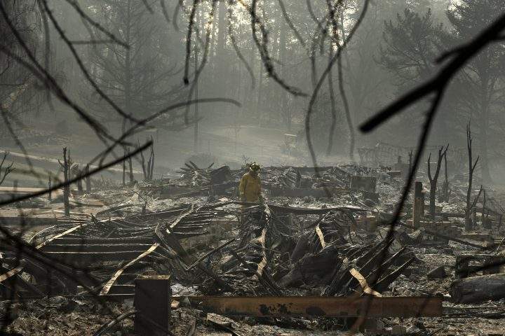 In this Friday, Nov. 16, 2018 file photo, a firefighter searches for human remains in a trailer park destroyed in the Camp Fire in Paradise, Calif. This town of 27,000 was destroyed in the deadliest, most destructive wildfire in California history.