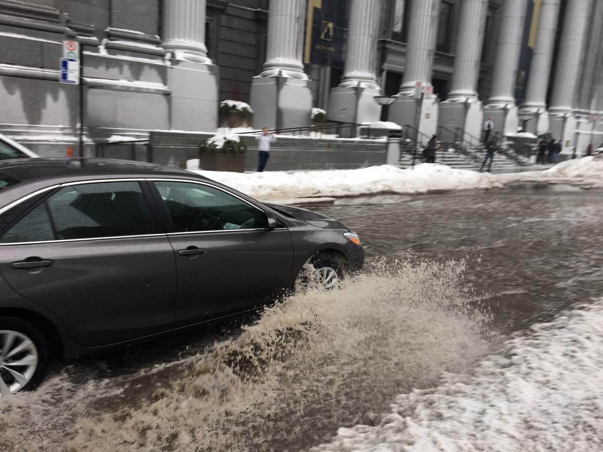 A car drives through a huge puddle of ice and water in downtown Montreal, Thurs., Jan. 24, 2019.
