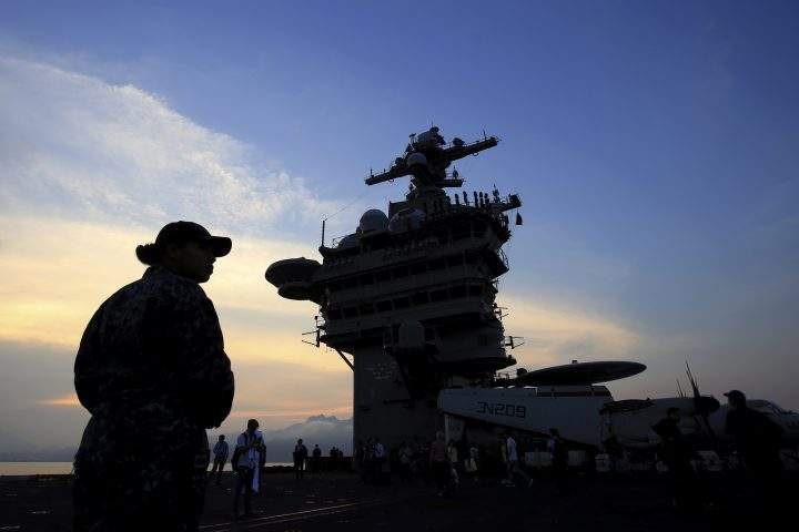 In this Monday, March 5, 2018 file photo, people stand on the deck of the USS Carl Vinson aircraft carrier as it docks in Danang bay, Vietnam.