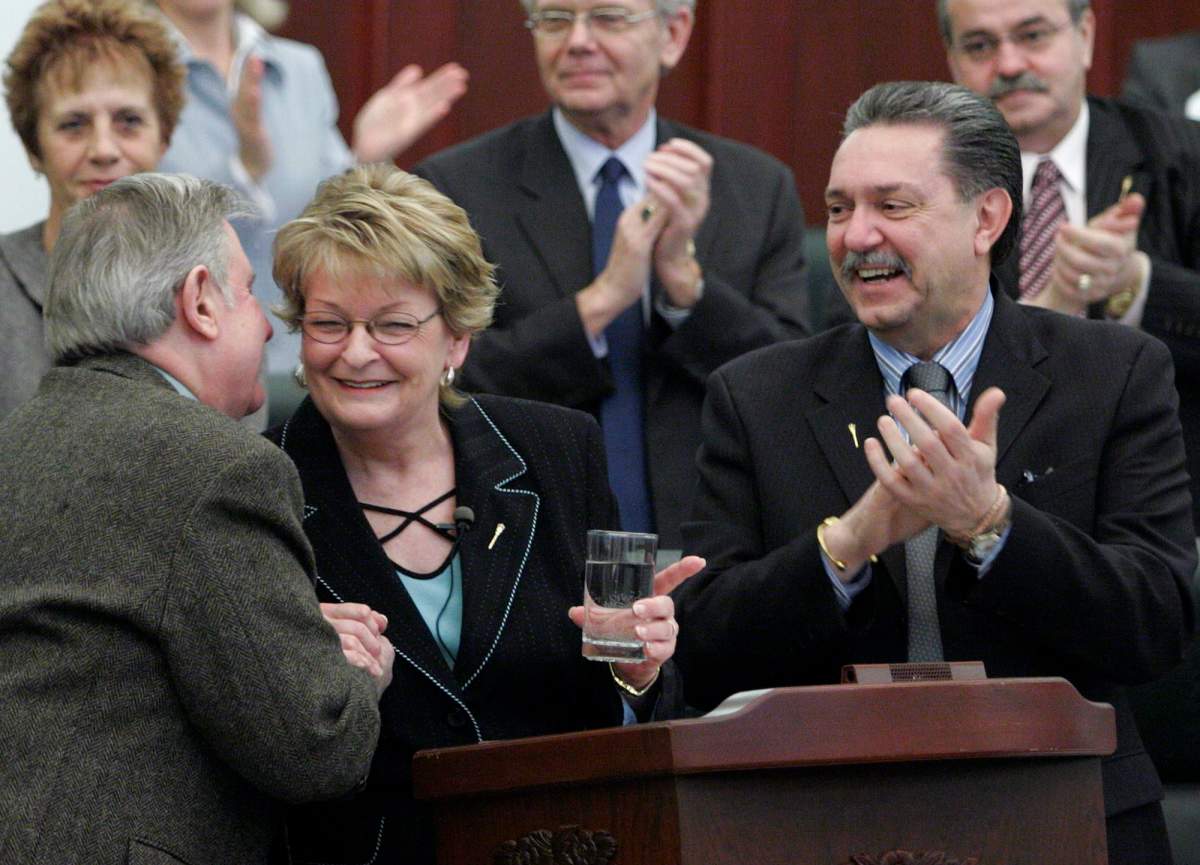 Minister of Education and Deputy Government House Leader, Gene Zwozdesky, right, looks on as Alberta Premier, Ralph Klein kisses Provincial Finance minister, Shirley McClellan, after she delivered her budget at the Alberta Legislature, in Edmonton, on Wednesday, March 22, 2006.