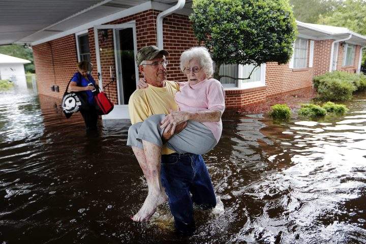 In this Sept. 17, 2018 file photo, Bob Richling carries Iris Darden, 84, out of her flooded home as her daughter-in-law, Pam Darden, gathers her belongings in the aftermath of Hurricane Florence in Spring Lake, N.C.