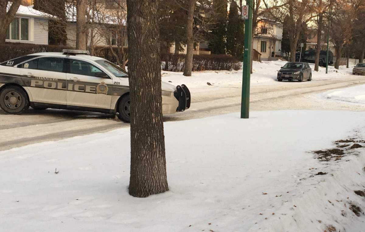 Winnipeg police on the scene while the WPS Armoured Vehicle sits next to the door of a duplex.