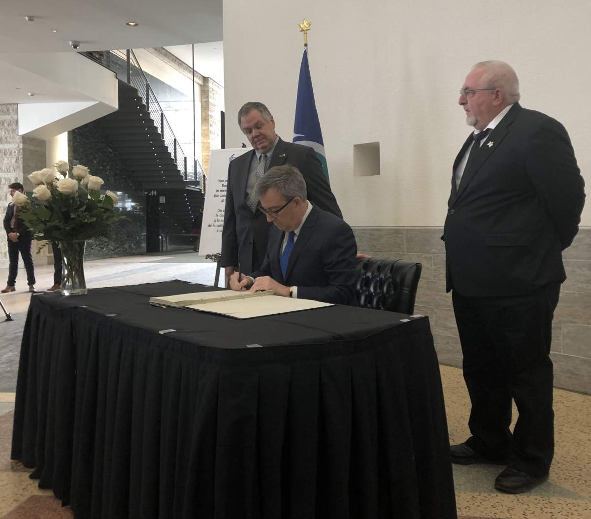 Ottawa Mayor Jim Watson signs a book of condolences honouring the victims of a deadly double-decker bus crash at Westboro station on Jan. 11. The vice-chair and chair of the transit commission Jean Cloutier (left) and Allan Hubley (right) also signed the book on Jan. 14.
