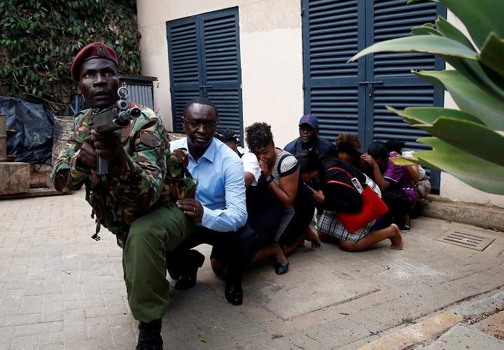 People are evacuated by a member of security forces at the scene where explosions and gunshots were heard at the Dusit hotel compound, in Nairobi, Kenya January 15, 2019.