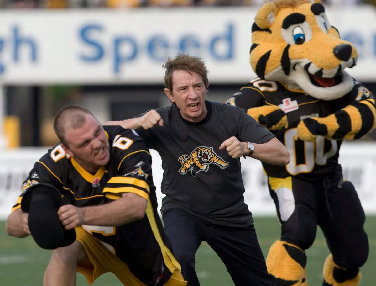 Comedian Martin Short (centre) leads a cheer with Pigskin Pete (left) and Hamilton Tiger-Cats mascot Stripes prior to CFL action against the Montreal Alouettes in Hamilton on Thursday June 26, 2008.