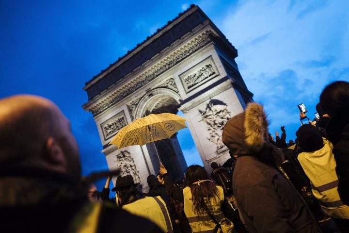 Demonstrators wearing yellow vests stand near the Arc de Triomphe as they gather in Paris, on Saturday, Dec. 22, 2018.