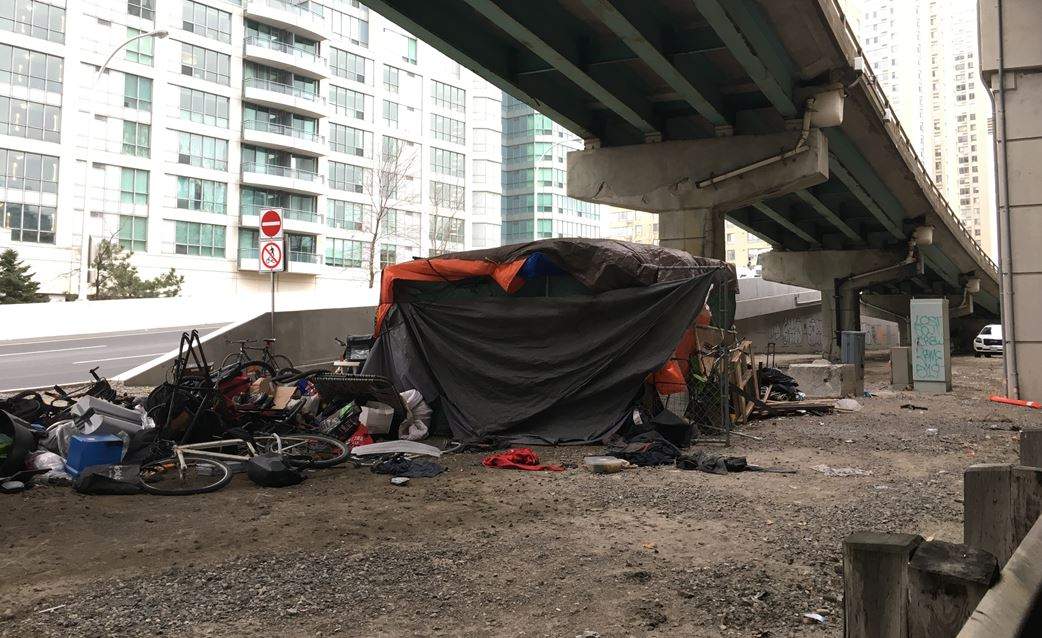 A person's tent and belongings can be seen under an on-ramp to the Gardiner Expressway in downtown Toronto.