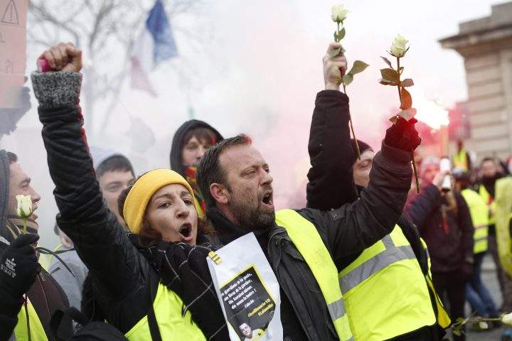 Yellow vest protesters hold white roses during a march Saturday, Jan. 19, 2019 in Paris.