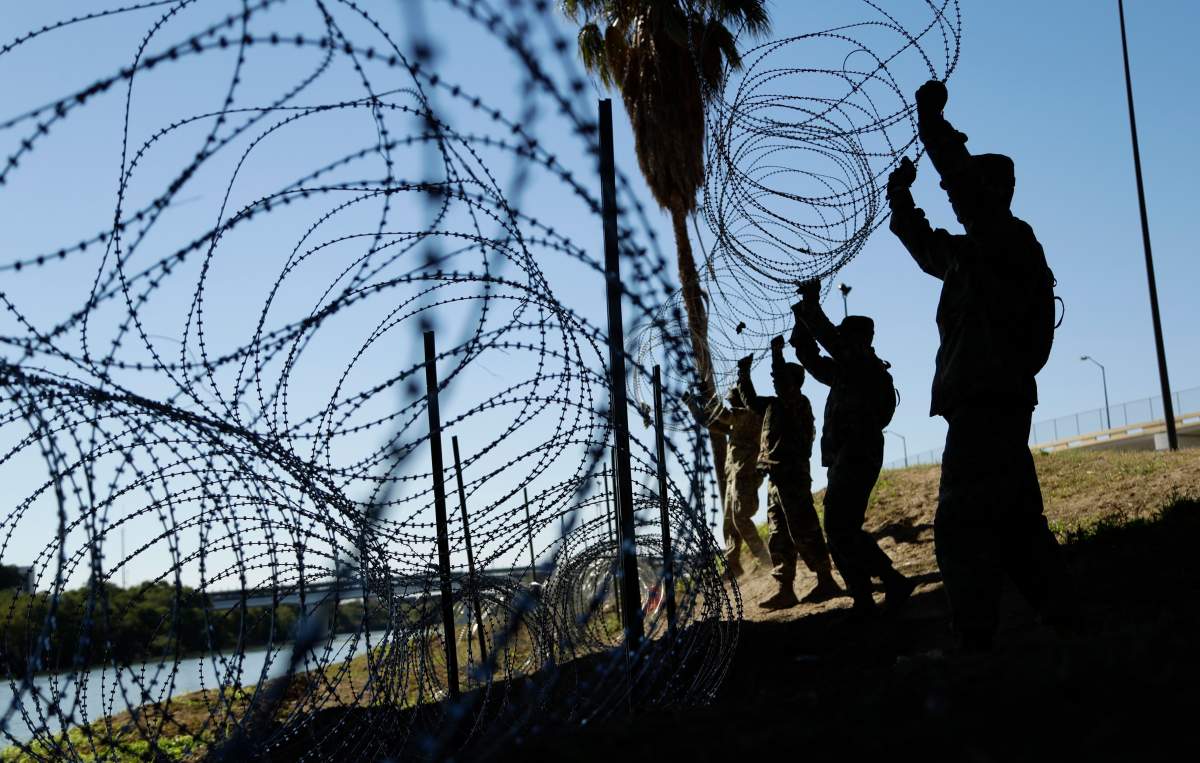 FILE - In this Nov. 16, 2018, file photo, members of the U.S. military install multiple tiers of concertina wire along the banks of the Rio Grande near the Juarez-Lincoln Bridge at the U.S.-Mexico border in Laredo, Texas.