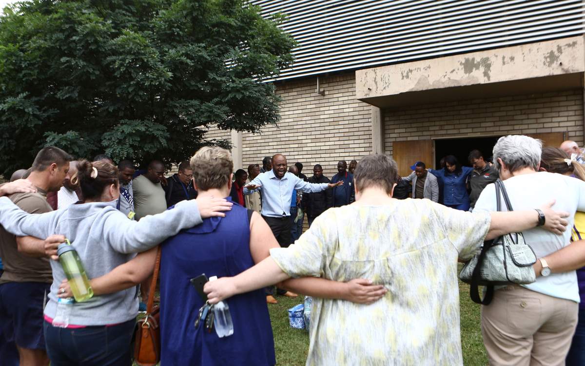 A pastor leads people in prayer at the site of a walkway collapse at the Driehoek High School in Vanderbijlpark, South Africa, Friday, Feb. 1, 2019. At least 3 students were killed and scores injured at the school near Johannesburg, a South African official said.