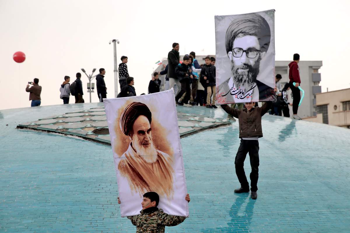 Two boys hold up posters of Iranian Supreme Leader Ayatollah Ali Khamenei, right, and late revolutionary founder Ayatollah Khomeini,left, during a rally marking the 40th anniversary of the 1979 Islamic Revolution, in Tehran, Iran, Monday, Feb. 11, 2019. (AP Photo/Ebrahim Noroozi)