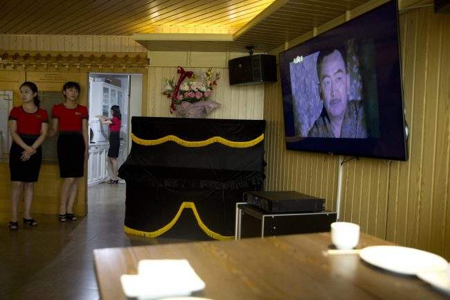 Waitresses stand near a television screen showing a period drama in Pyongyang, North Korea, Aug. 15, 2018.