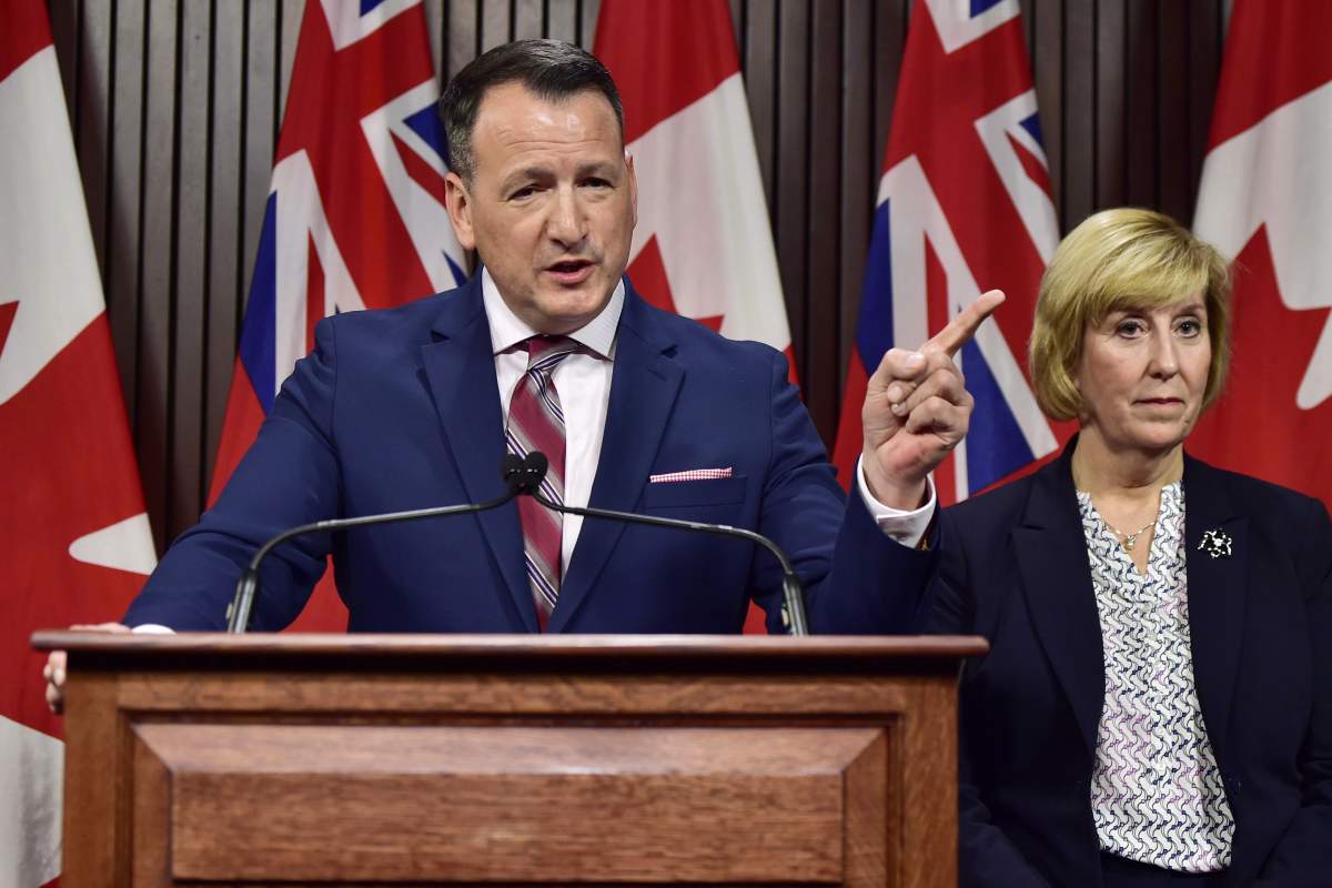 Ontario's Energy Minister Greg Rickford speaks as Labour Minister Laurie Scott looks on during a press conference at Queen's Park in Toronto on Monday, Dec. 17, 2018. Ontario's energy minister says the government will take "any and all action necessary" if Hydro One doesn't drastically cut its proposed CEO compensation, but the semi-private utility appears not to be budging. 