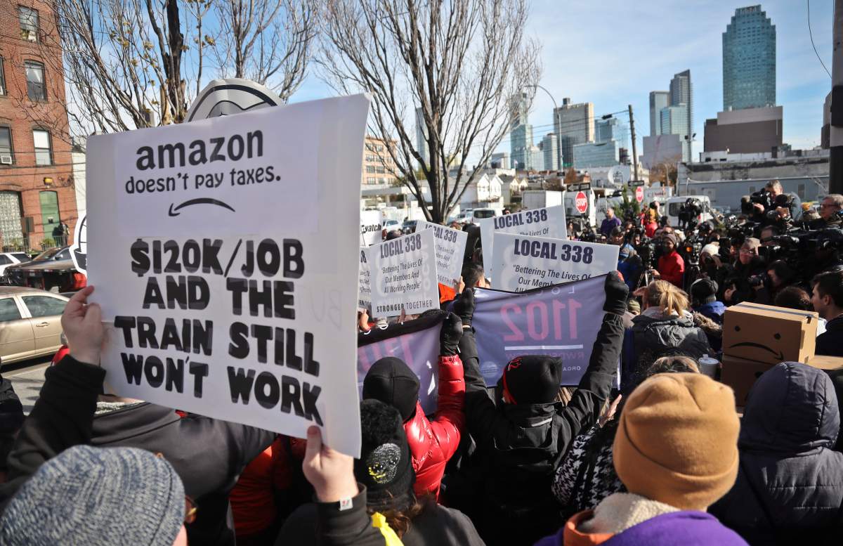 FILE – In this Nov. 14, 2018, file photo protesters carry anti-Amazon posters during a coalition rally and press conference opposing Amazon headquarters getting subsidies to locate in the New York neighborhood of Long Island City in the Queens borough of New York. Some residents wondered why one of the world’s most valuable companies needed nearly $3 million in tax incentives to come to New York.