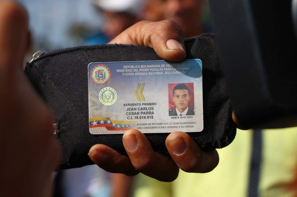 Defected Venezuelan National Guard sergeant Jean Carlos Cesar Parra shows his ID to the press after crossing the border to Pacaraima, Brazil, Sunday, Feb. 24, 2019 during a confrontation over aid shipments for Venezuela as its government closes its borders with Brazil and Colombia.
