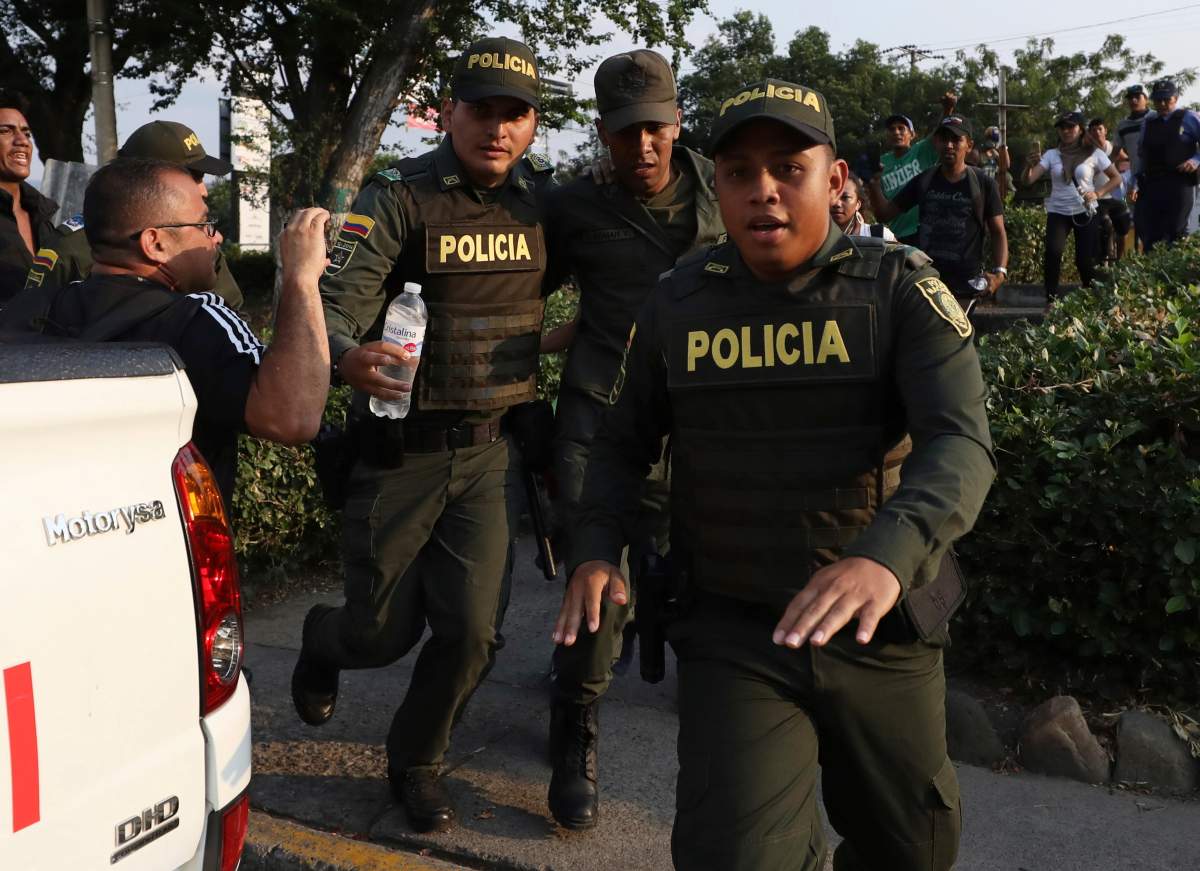 A Venezuelan National Guard, centre, deserts his post as Colombian Police escort him after he managed to cross the Simon Bolivar International Bridge where his fellow guardsmen are blocking the entry of U.S.-supplied humanitarian aid, in La Parada, Colombia, Monday, Feb. 25, 2019, on the border with Venezuela.
