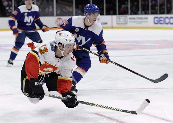 Calgary Flames left wing Johnny Gaudreau (13) trips after taking a shot on goal in the first period of an NHL hockey game against the New York Islanders, Tuesday, Feb. 26, 2019, in Uniondale, as Islanders defenseman Thomas Hickey (4) watches his goalie.